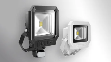 Das Bild zeigt schräg von der Seite zwei OFL/AFL SUN LED Außenstrahler nebeneinander. Der linke Außenstrahler hat ein weißes Gehäuse und ist klener als der rechte. Der rechte OFL/AFL SUN LED Außenstrahler ist schwarz und ist in etwa doppelt so groß wie der linke Außenstrahler. Der Bildhintergrund ist grau-weiß.