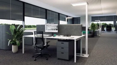 Das Bild zeigt eine schlanke, moderne Stehleuchte in einem Büro, die für direkte und indirekte Beleuchtung sorgt und sich durch schlichtes Design und helle Lichtwirkung auszeichnet.