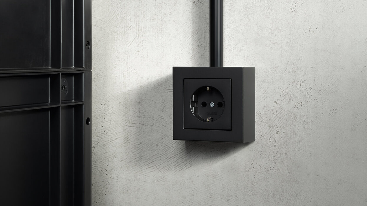 Steckdose in der Farbe Schwarz an der Wand montiert.