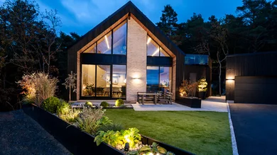 Blick auf ein modernes Einfamilienhaus mit Strahlern in der Dämmerung.