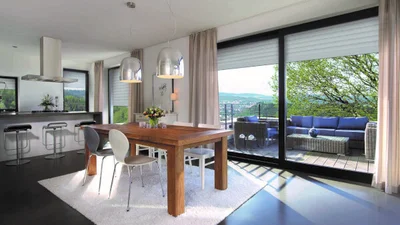 Wohn/-Esslandschaft mit großem Fenster und Balkon auf der eine Sitzlandschaft steht.