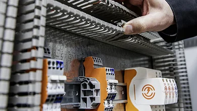 Ausschnitt aus einem Überspannungsschutz-System von OBO Bettermann und eine Hand, die auf etwas im System zeigt.