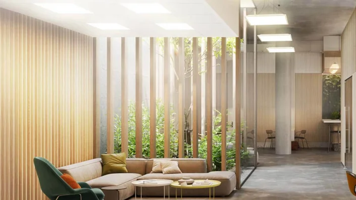 Das Bild zeigt ein modernes, lichtdurchflutetes Büro mit großen Glasflächen, Holzlamellen und viel Grün. Quadratische, flache Deckenleuchten sorgen für eine gleichmäßige und angenehme Beleuchtung im Raum.
