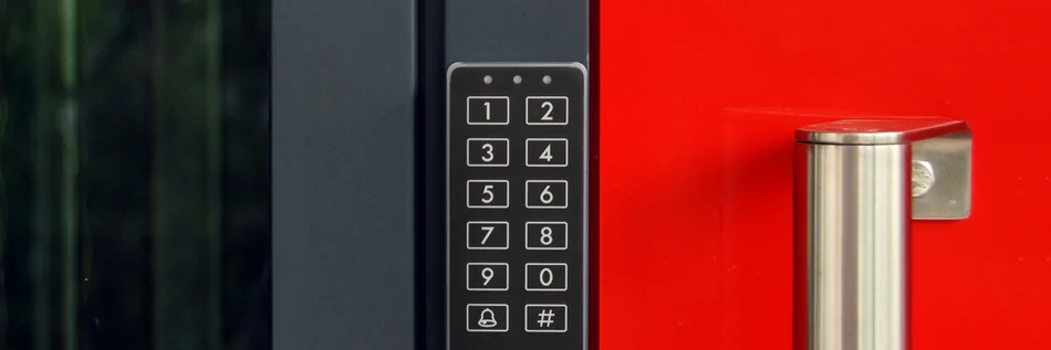 Das Bild zeigt ein Zutrittskontrollsystem mit beleuchteter Tastatur an einer modernen Eingangstür.