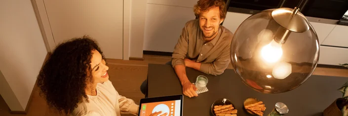 Zwei Personen, von oben fotografiert, am Tisch sitzend. Abendstimmung.
