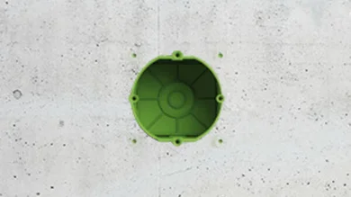 Das Bild zeigt eine graue Wand, in der ein Loch ist. Man sieht in dem Loch die Farbe Grün.