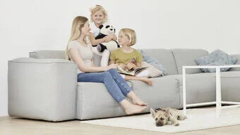 Eine Person sitzt zwei Kindern auf dem Sofa.