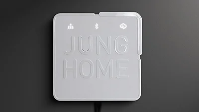 Schalter mit der Aufschrift Jung Home in der Farbe Grau vor einem dunkelgrauen Hintergrund.