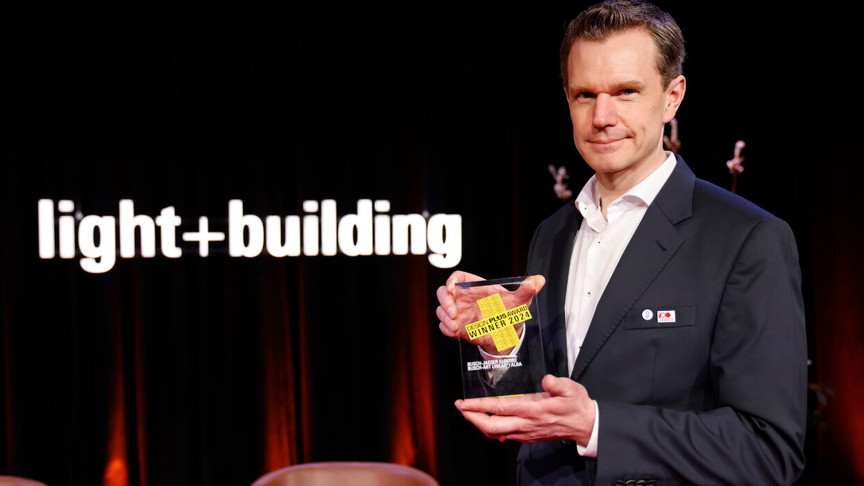 Person, die den Designplus Award in der Hand hält.
