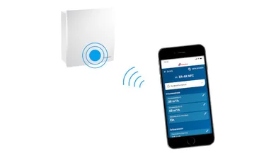 Das Bild zeigt ein weißes MAICO-Gerät und ein Smartphone. Zwischen Gerät und Smartphone sind stilisierte, blaue Funkwellen dargestellt. Auf dem Display des Smartphones sind Einstellmöglichkeiten für Volumenstrom und Zeitparameter zu sehen. 