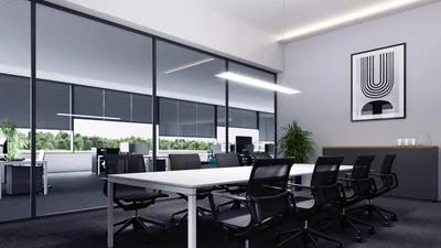 Das Bild zeigt einen modernen, hellen Konferenzraum mit großem Tisch, mehreren schwarzen Bürostühlen und Glaswänden, die den Blick ins Büro freigeben.