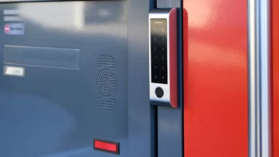 Das Bild zeigt ein modernes Zutrittskontrollsystem mit Touch-Tastatur an einer farbigen Eingangstür.