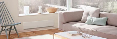 In einem Wohnzimmer ist ein Raumheizgerät unter dem Fenster an der Wand befestigt.