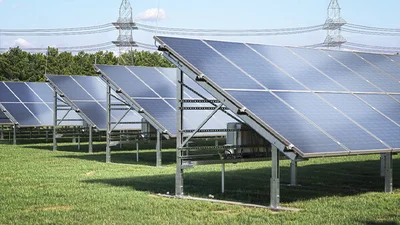Das Bild zeigt Reihen von Solarpanels auf einer Rasenfläche.