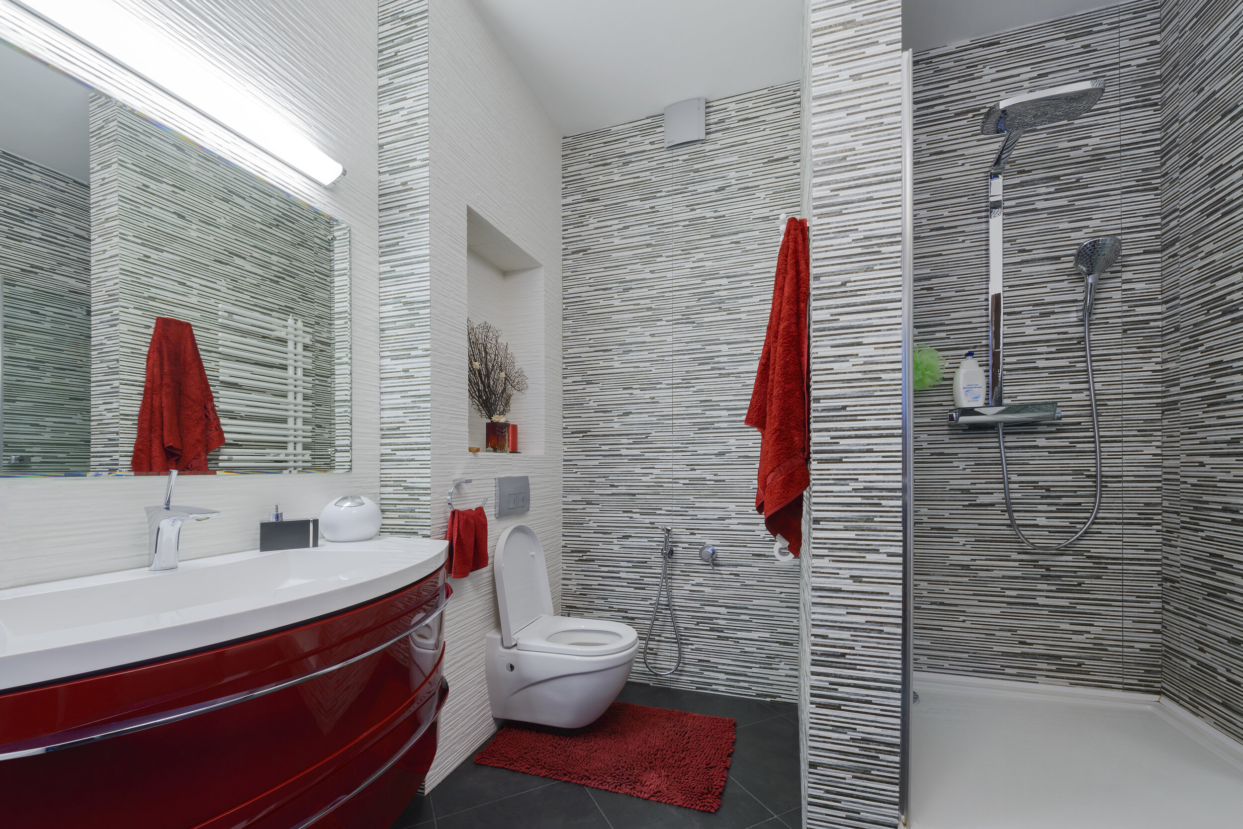 Dieses Bild zeigt ein modern eingerichtetes Badezimmer in weiß mit roten Designelementen.