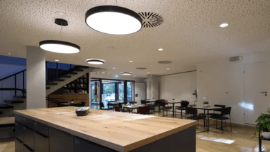 In einem großem Raum mit vielen Sitzgruppen sind über einem Küchenblock große, runde Leuchten angebracht.