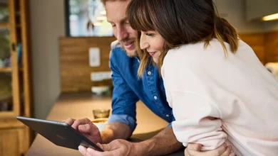 Das Bild zeigt ein Paar, das gemeinsam auf ein Tablet schaut.