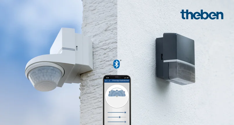 ChatGPT: Das Bild zeigt zwei an Wänden montierte Bewegungsmelder. Links ist ein weißes Gerät zu sehen, rechts ein schwarzes. In der Mitte befindet sich ein Smartphone mit einer geöffneten App, die Einstellungen für die Empfindlichkeit anzeigt. Oben rechts steht das Logo „theben“.
