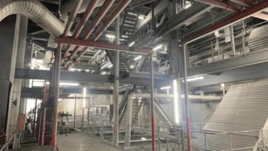 Das Bild zeigt einen großen Raum mit Stützpfeilern aus Metall, vielen Metallrohren und Metallgestängen. Im Raum verteilt sind Leuchten der Serie MISTRALeco längs und quer angebracht. 