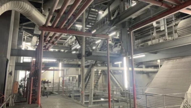 Das Bild zeigt einen großen Raum mit Stützpfeilern aus Metall, vielen Metallrohren und Metallgestängen. Im Raum verteilt sind Leuchten der Serie MISTRALeco längs und quer angebracht. 