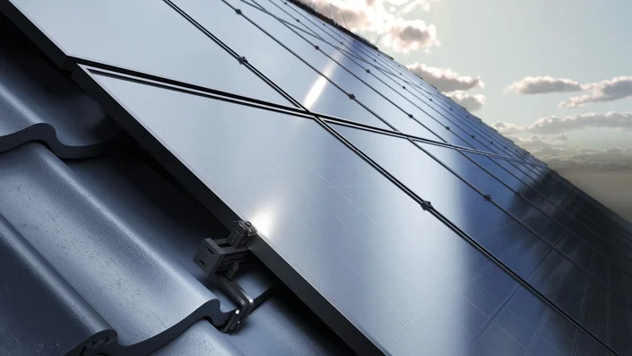 Das Bild zeigt eine Fläche schwarzer Solarpanels. Der linke Bildbereich zeigt die Befestigung eines Panels an einem dunklen Dachziegel.