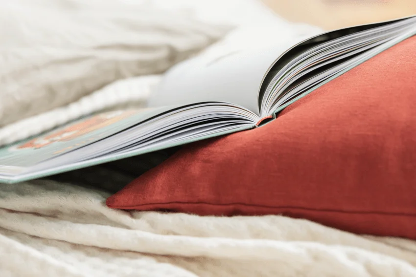 Das Bild zeigt ein augeschlagenes Buch auf einem Sofa oder Bett.