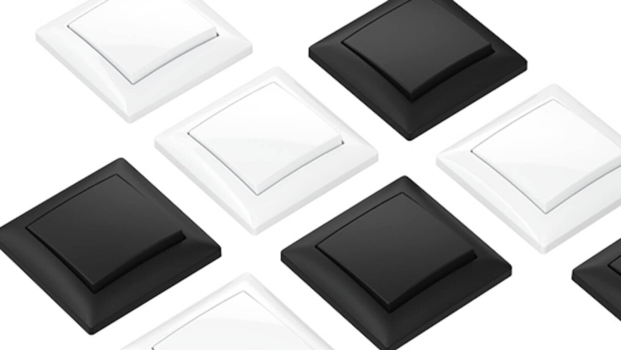 Das Bild zeigt mehrere quadratische Wandschalter in Schwarz und Weiß, schräg angeordnet auf weißem Hintergrund.