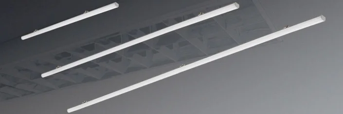 Das Bild zeigt drei schmale, längliche LED-Deckenleuchten in schlichtem Design und unterschiedlicher Länge, die an einer grauen Decke montiert sind.
