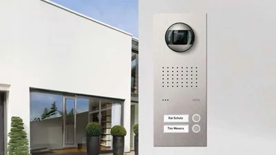 Blick auf das Türstationenmodell Acero von Ritto und im Hintergrund ein modernes weißes Gebäude.