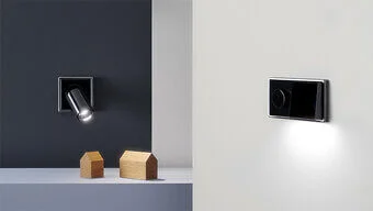 Abdeckung für Beleuchtungen. Ein LED Spot ist an einer grauen Wand montirt.