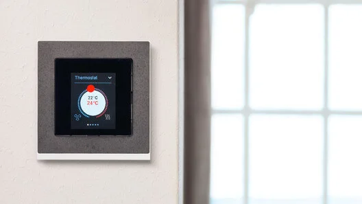 Großes Bedienfeld an der Wand montiert. Dahinter ein heller Raum mit Fenster.