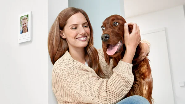 Das Bild zeigt eine Person mit einem Hund vor einer Wand mit Busch-WelcomePanel® 