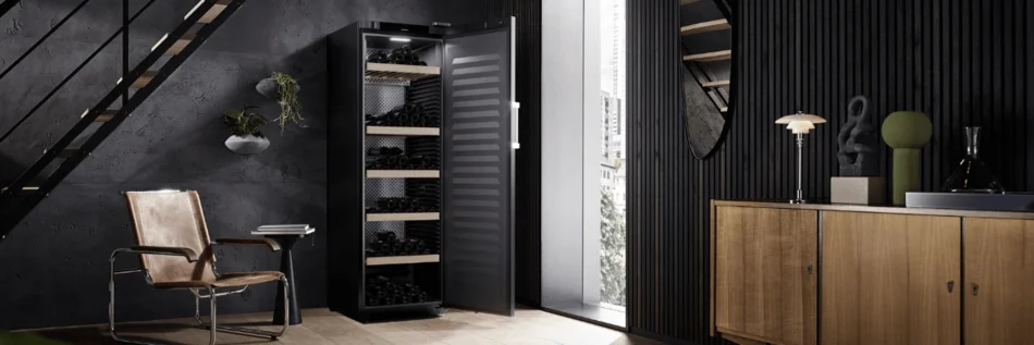 Eleganter und in der Farbe Schwarz gehaltener Wohnraum mit großem Weinkühlschrank in der Farbe schwarz, der geöffnet ist.