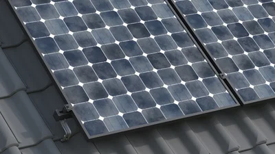 Das Bild zeigt eine Fläche schwarzer Solarpanels auf einem dunklen Dach.