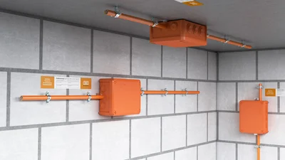 Boxen in der Farbe Orange, die an einer unverputzten Wand montiert sind.