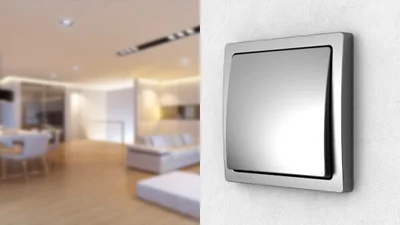 Schalter Delta von Siemens in der Farbe Grau an der Wand und im Hintergrund eine Wohnlandschaft. 