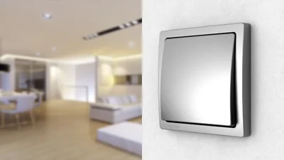 Schalter Delta von Siemens in der Farbe Grau an der Wand und im Hintergrund eine Wohnlandschaft. 