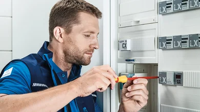 Auf diesem Bild ist eine Person zu sehen, die gerade bei der Montage vor einem Schaltschrank ist.