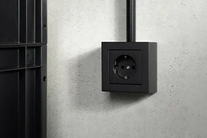 Steckdose in der Farbe Schwarz an der Wand montiert.